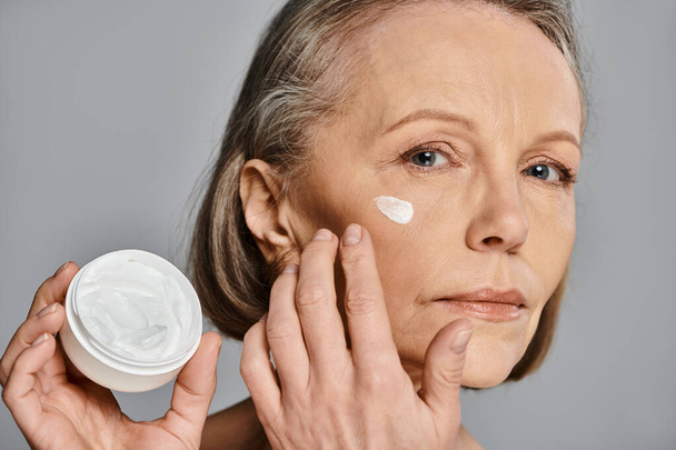 A woman nourishing her skin with cream in a self-care moment. - Photo, Image