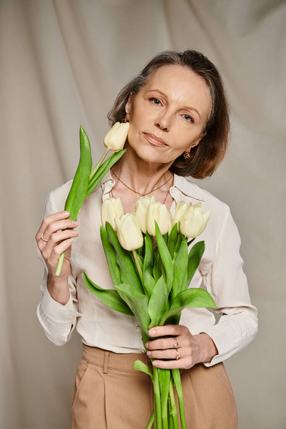Mulher madura alegremente segurando um buquê de tulipas brancas. - Foto, Imagem