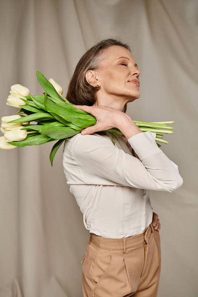 Anmutig hält Frau einen Strauß lebendiger Tulpen in der Hand. - Foto, Bild