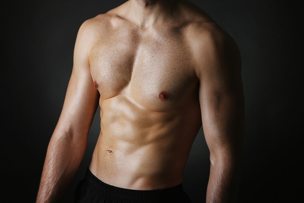 Muscle young man on black background - Valokuva, kuva