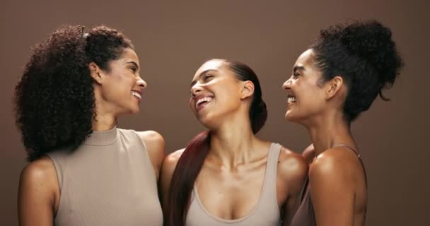 Women, face and group for beauty in studio for smile, solidarity or care with hug for skin by brown background. Girl friends, people and model for skincare, hug or natural makeup for facial cosmetics. - Footage, Video