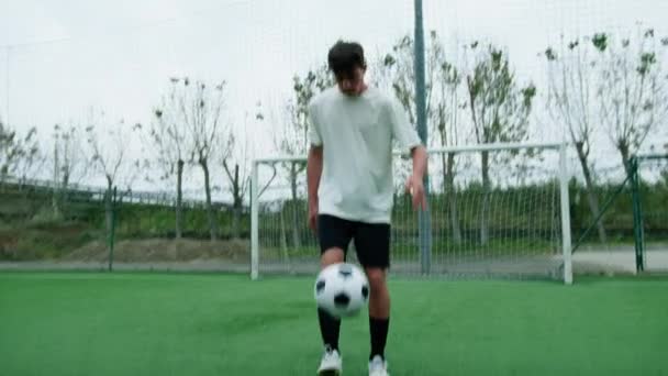 Підліток дриблінг з футбольним м'ячем біля мети. - Кадри, відео