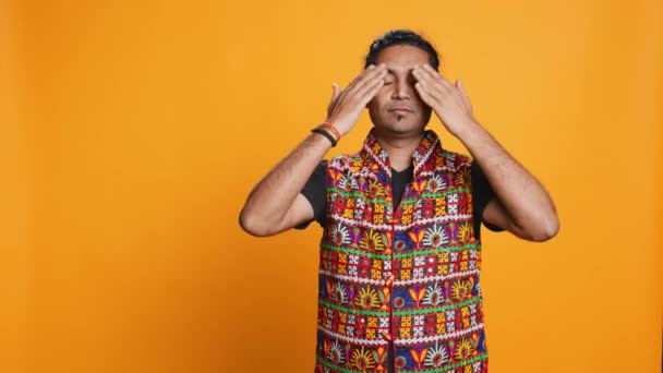 Man wearing traditional indian clothing covering eyes, ears and mouth, imitating three wise monkeys, doing dont see, dont hear and dont speak hand gesturing concept, studio background, camera B - Footage, Video