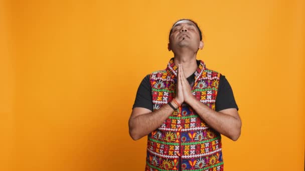 Hurskas intialainen rukoilee jumalaansa anteeksiantoa. Hengellinen henkilö, joka palvoo kättä elehtien, tunnustaen, rukoillen anteeksiantoa, eristettynä studion taustalta, kamera B - Materiaali, video