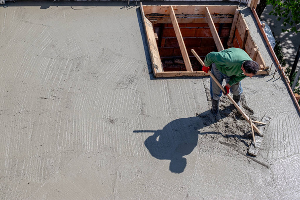 Bauarbeiter nivelliert Beton auf einer Dachplatte. - Foto, Bild
