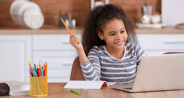 Little African-American girl doing homework in kitchen - Photo, Image