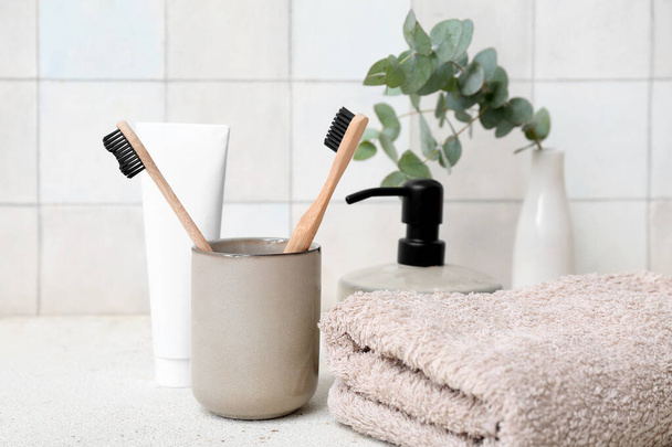 Set di forniture da bagno con spazzolini da denti sul tavolo contro la parete di piastrelle leggere - Foto, immagini