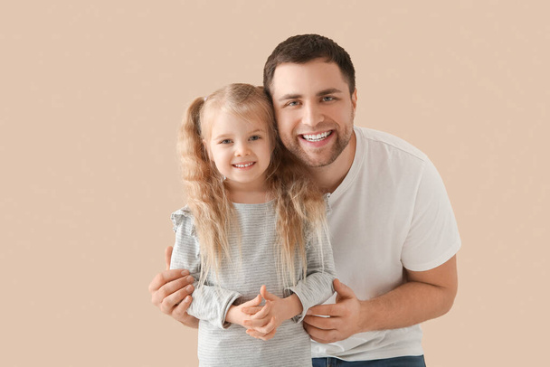 Мила щаслива дівчинка з батьком на бежевому фоні - Фото, зображення