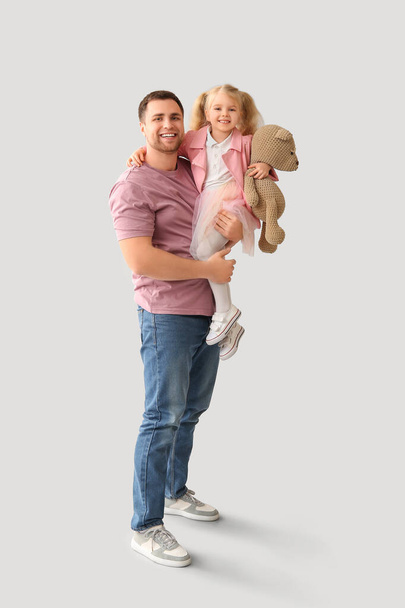Felice padre e la sua figlioletta carina con orsacchiotto su sfondo grigio - Foto, immagini