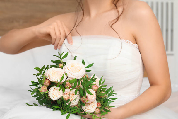 Νεαρή νύφη με γαμήλιο μπουκέτο στην κρεβατοκάμαρα, κοντινό πλάνο - Φωτογραφία, εικόνα