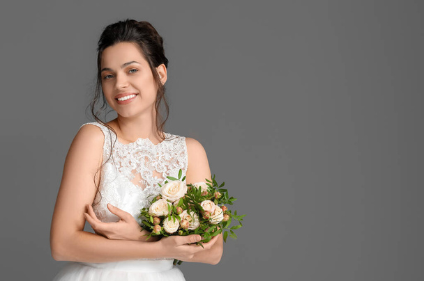 Mooie jonge bruid met bruiloft boeket op donkere achtergrond - Foto, afbeelding