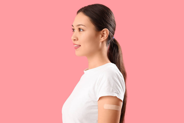 Beautiful young woman with applied medical patch on pink background - Photo, Image