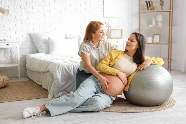 Jeune femme enceinte avec fitball et doula formation dans la chambre - Photo, image