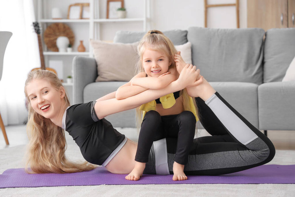Jovem esportiva com sua filha treinando em casa - Foto, Imagem