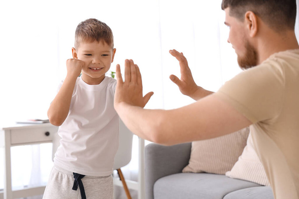 Молодой человек и его маленький сын боксируют в гостиной - Фото, изображение