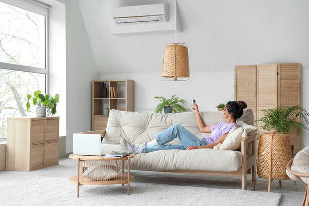 Mladá Afroameričanka zapíná doma klimatizaci - Fotografie, Obrázek