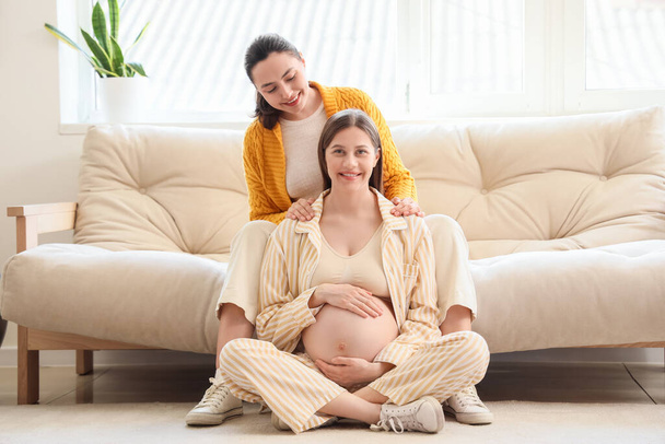 Jovem grávida com doula sentada em casa - Foto, Imagem
