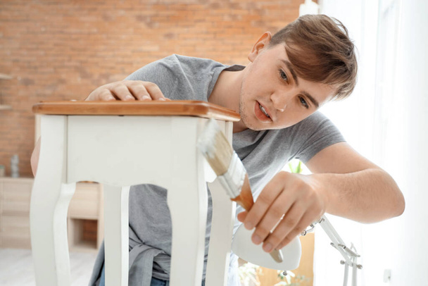 Young man with brush painting table at home - Photo, Image