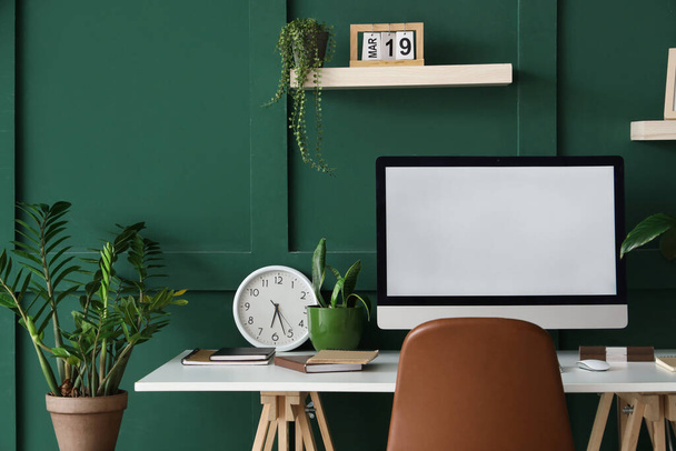 Blank computer monitor with clock on table and plants in office - Photo, Image