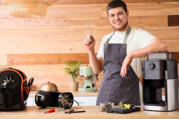 Trabalhador masculino com chave de fenda reparando máquina de café na cozinha - Foto, Imagem