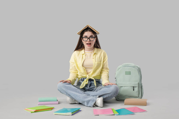 Estudiante femenina con libros sentados sobre fondo claro - Foto, Imagen