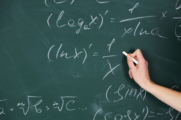 Female hand writing formulas on blackboard with chalk, close up - Fotó, kép