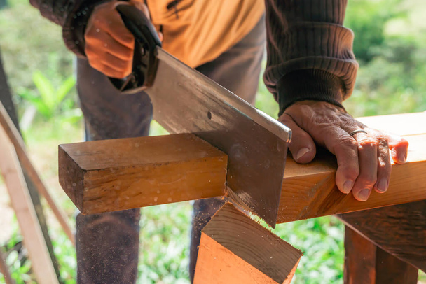 Homme plus âgé travaillant à la maison avec une scie à main. Latino couper le bois et réparer. Outils de menuiserie. - Photo, image