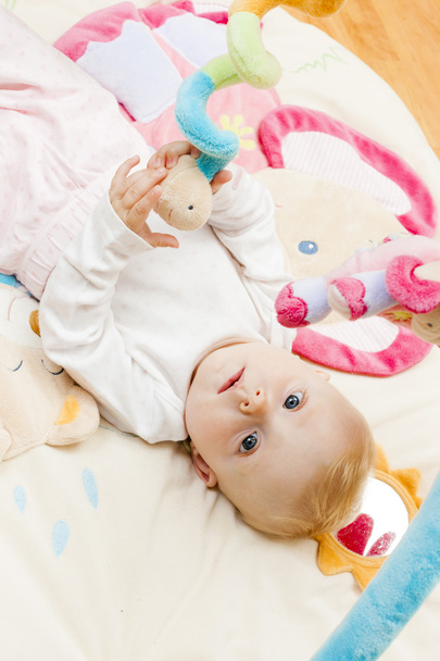 Portret van meisje van de baby liggend op de mat spelen - Foto, afbeelding