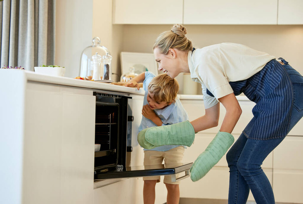 Keuken, moeder en zoon binding, oven en kind met nieuwsgierigheid, bakken en helpen van moeder met gezond eten. Home, vrouw en jongen leren brood bereiden, koken en samen met ouders en avondeten. - Foto, afbeelding