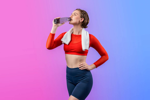 Teljes testhossz vidám lövés sportos és sportos fiatal nő törölközővel és ivóvíz fitness testtartás elszigetelt háttérrel. Egészséges aktív és testápoló életmód. - Fotó, kép