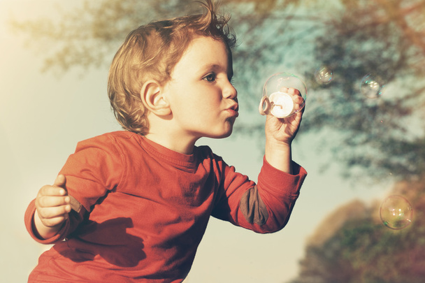 Little boy blowing soap bubbles - Фото, изображение