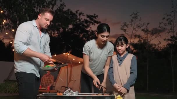 Family together camp in garden, Mom dad and daughter grill food for family member. Outdoor camping activity to relax with nature and spend time with young generation cross generation gap. Divergence. - Footage, Video