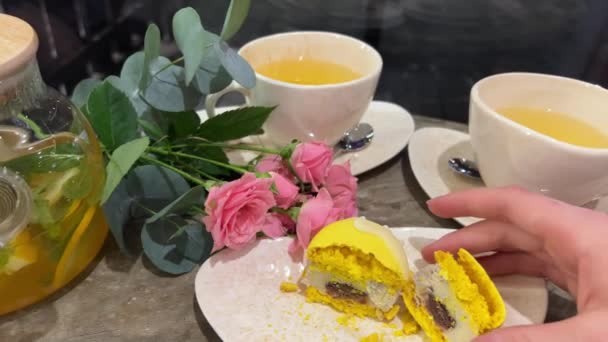 vrouwelijke hand verkruimelt achteloos en snijdt macarons met Frans dessert met mes op een glazen tafel close-up gele citroen. macarons met papaverzaadvulling - Video