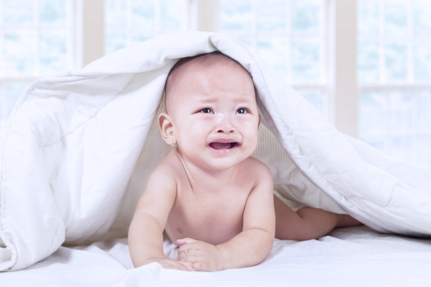 Baby crying under blanket at home - Foto, afbeelding