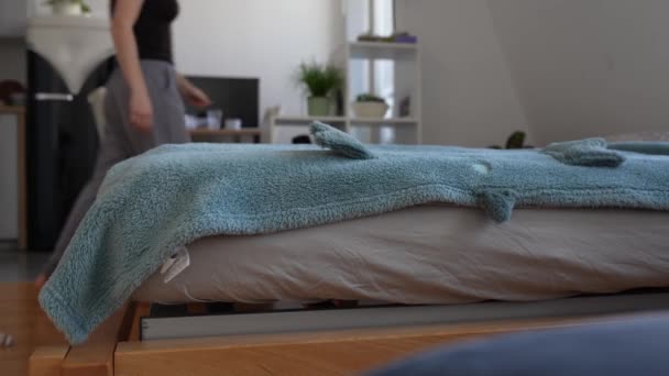 nuori punatukkainen kihara nainen tekee sängyn peitto, aamu, kotitehtävät, hoito - Materiaali, video