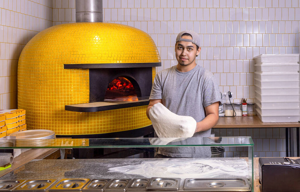 Chef preparando masa de pizza. El proceso de hacer pizza. Chef experto preparando masa para rodar pizza con las manos mientras trabaja en una pizzería. El proceso de elaboración de pizzas. - Foto, imagen