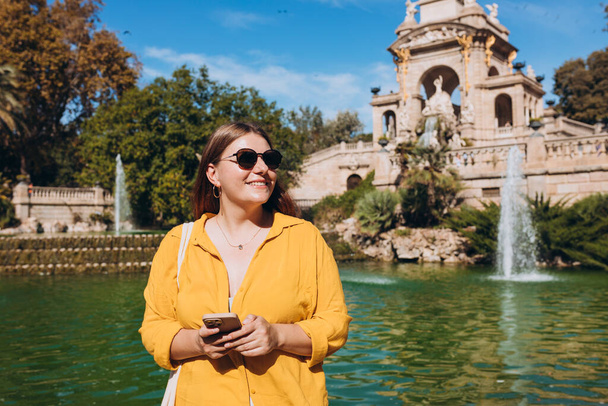 Nuori nainen turisti puhelimitse vierailevat Ciutadella Park Barcelonassa. Käsite matka, matkailu ja loma kaupungissa. Käytä teknologian käsitettä - Valokuva, kuva