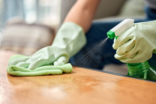 Table, cleaning service and hand of person with bottle for hospitality, work and safety in hygiene. Cloth, spray and cleaner with product in hotel for maintenance, bacteria removal and housekeeping. - Photo, Image