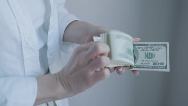 Μια εικόνα που αιχμαλωτίζει τα χέρια σε ένα λευκό πουκάμισο καθώς μετρούν χαρτονομίσματα των 100 δολαρίων, εστιάζοντας στη δυναμική του πλούτου και των συναλλαγών - Πλάνα, βίντεο