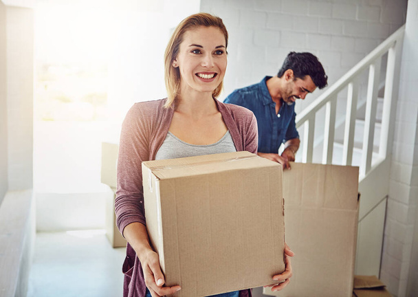Couple, moving and new home with boxes, sunshine and happiness with mortgage, real estate and achievement. Apartment, man and woman with package, cardboard and property with lens flare and excited. - Photo, Image
