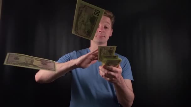 a dashing young man enthusiastically counts a stack of dollar bills. The thrill of a life-changing stroke of luck on the simple black backdrop. The epitome of celebratory joy after hitting the jackpot - Footage, Video