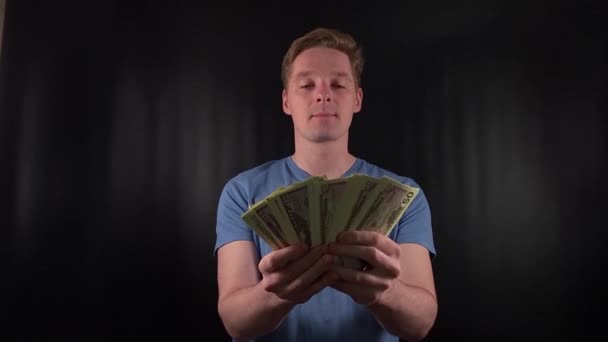 a dashing young man enthusiastically counts a stack of dollar bills. The thrill of a life-changing stroke of luck on the simple black backdrop. The epitome of celebratory joy after hitting the jackpot - Footage, Video