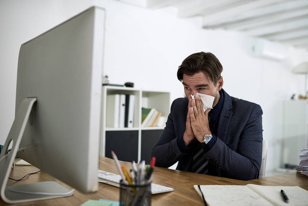 Синус, чихание и деловой человек в офисе с аллергией, высморкающийся нос и вирус работают за столом. Корпоративный работник, здравоохранение и человек с тканями от болезней, простуды и чихания гриппа на рабочем месте. - Фото, изображение