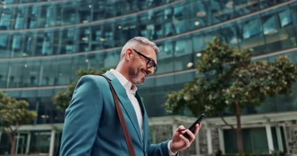 Homme d'affaires, sourire et téléphone portable avec ville, notification et trajet pour l'espace de travail. Homme âgé, heureux et téléphone avec des lunettes, bureau et marcher pour la communication d'entreprise ou b2b à Cape Town avec PDG. - Séquence, vidéo