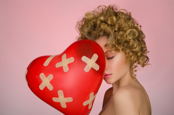 Unhappy young woman with ball in shape of heart - Foto, imagen