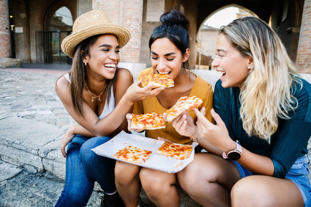 休暇旅行や休日のライフスタイルのコンセプトでイタリアのピザを食べて楽しい3人の多民族観光客の友人. - 写真・画像