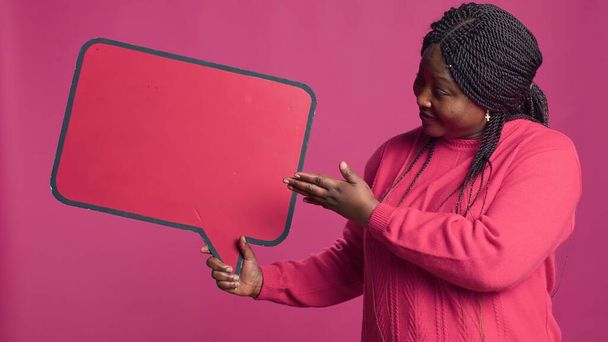 Afrikai szépség megragadta a piros beszéd buborék mockup jobb kézben szöveges üzenetek és jegyzetek. Fekete nő jóváhagyása információ szó buborék copyspace sablon. - Fotó, kép