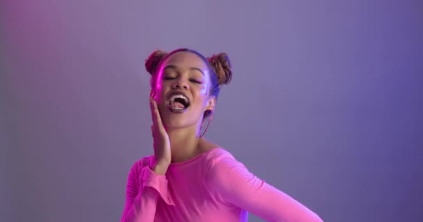 Woman, beauty and makeup with funny face, crazy and goofy with earrings and glitter on purple background. Fun, playful and pout in portrait with cosmetology, space buns hairstyle and funky style. - Footage, Video