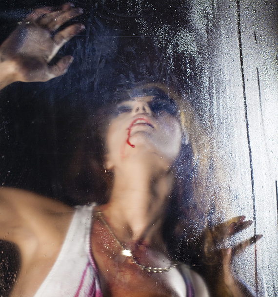 Terrible and bloody woman looking through wet glass - Foto, Imagem