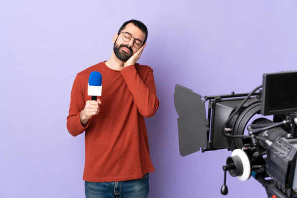 Homem repórter segurando um microfone e relatando notícias sobre fundo roxo isolado fazendo gesto de sono em expressão adorável - Foto, Imagem